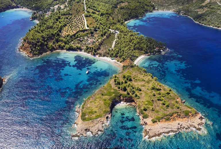 Aerial of forested peninsulas, islets and turquoise shallows with small beaches