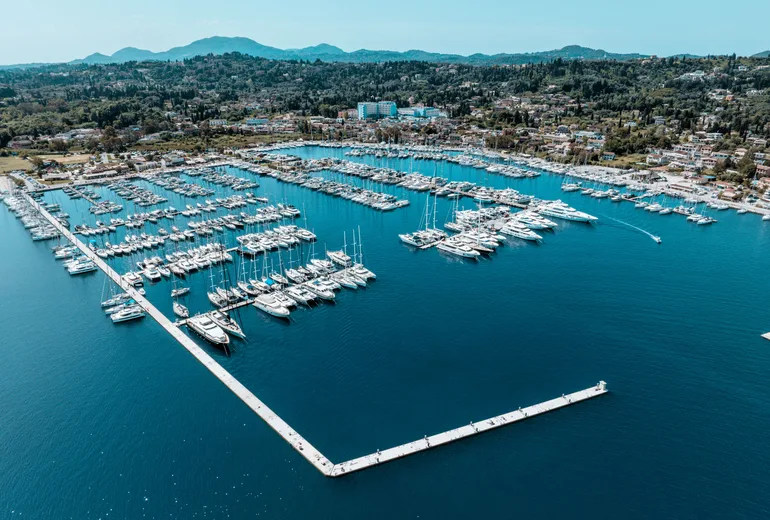 Aerial view of a large marina with rows of sailboats and wooded hills