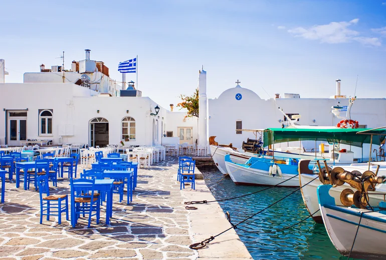 Blue taverna tables and traditional fishing caiques in Naoussa port, Paros