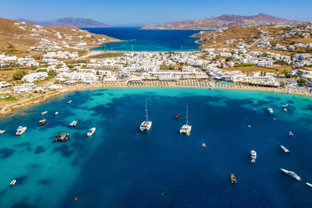 Aerial of Ornos bay on Mykonos with anchored catamarans and beach clubs