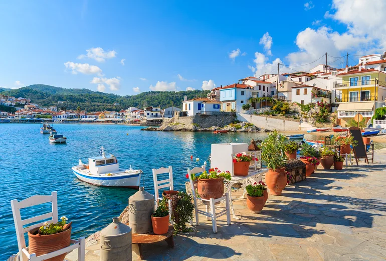 Flower pots, chairs and fishing boats on the waterfront of Kokkari village, Samos