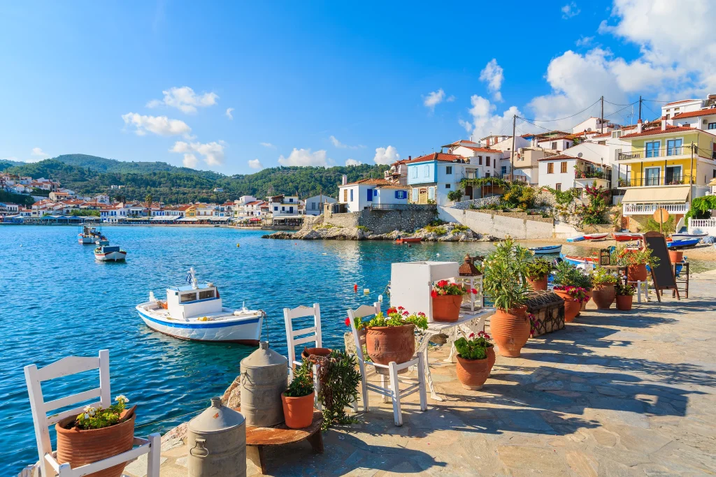 Flower pots, chairs and fishing boats on waterfront of Kokkari village, Samos