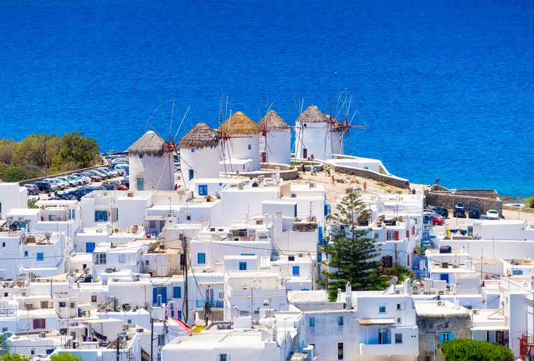 Iconic windmills above the whitewashed houses of Mykonos Town and deep blue sea