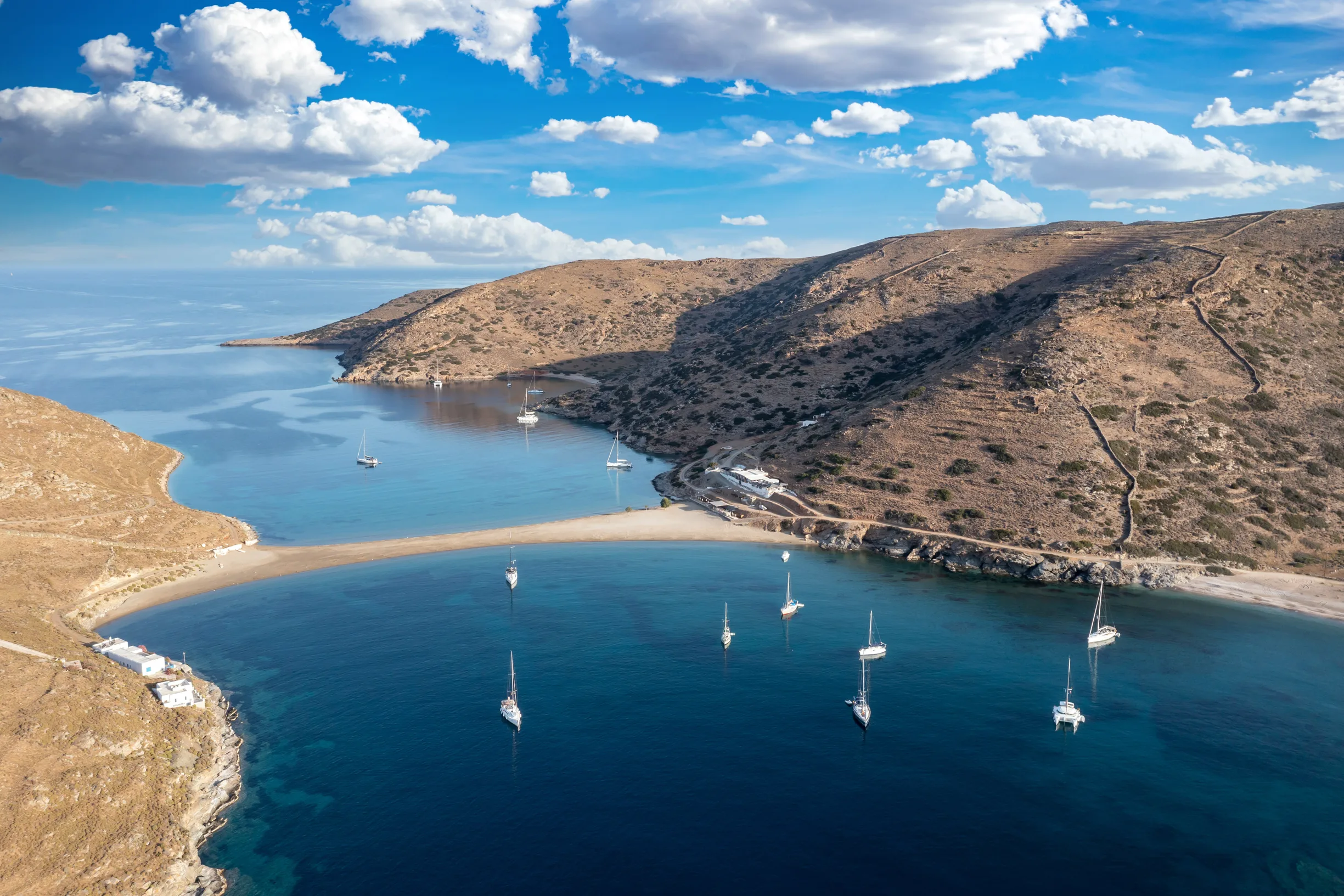 Aerial of Kolona sandbar on Kythnos with sailboats anchored both sides