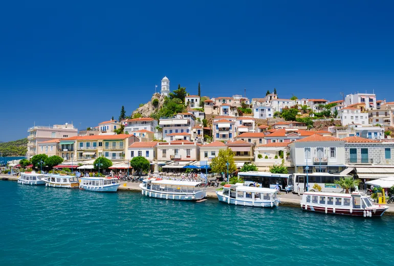 Poros town waterfront with the clock tower hill and excursion boats