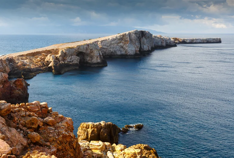 Rugged pale limestone headland jutting into a dark sea under a moody sky