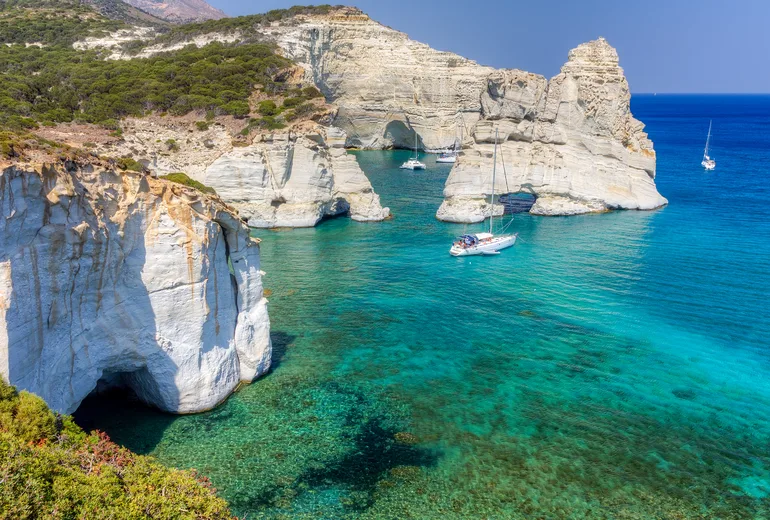 Sailing yachts anchored beneath the white sculpted cliffs of Kleftiko on Milos