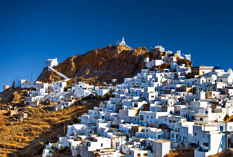 Whitewashed houses of Serifos Chora stacked beneath a rocky hilltop chapel